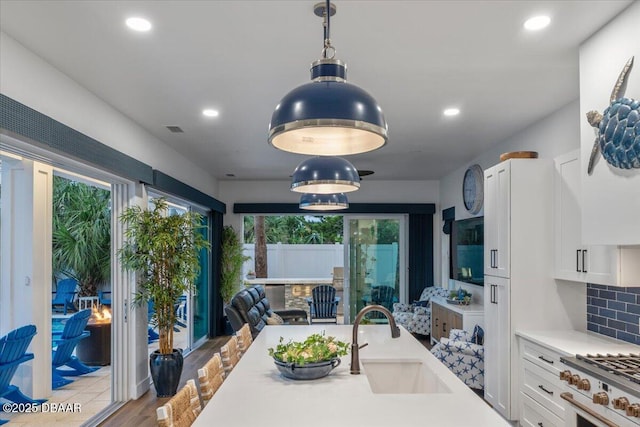 kitchen featuring visible vents, a sink, open floor plan, white cabinets, and light countertops