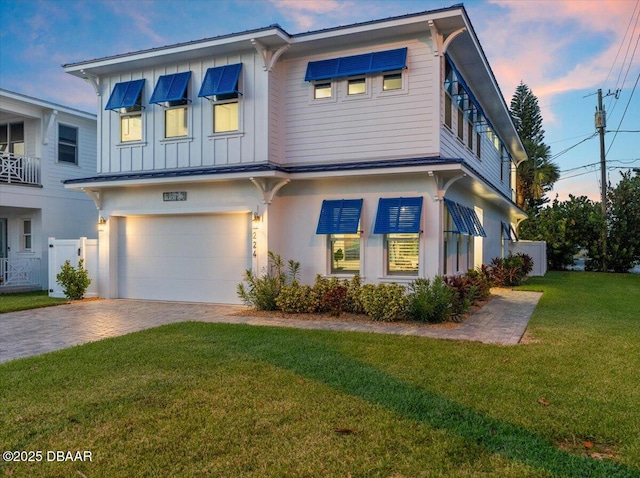 view of front of house featuring decorative driveway, fence, board and batten siding, a front yard, and a garage