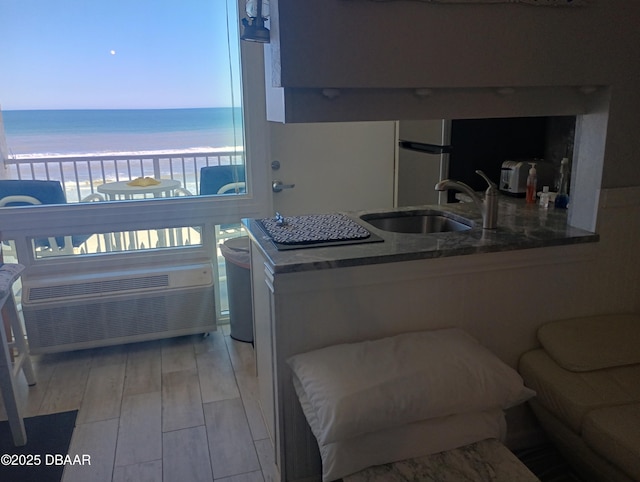 kitchen featuring dark stone countertops, light wood finished floors, refrigerator, a sink, and a water view