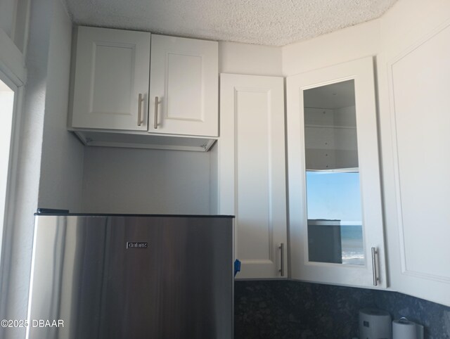 kitchen featuring a textured ceiling and white cabinets