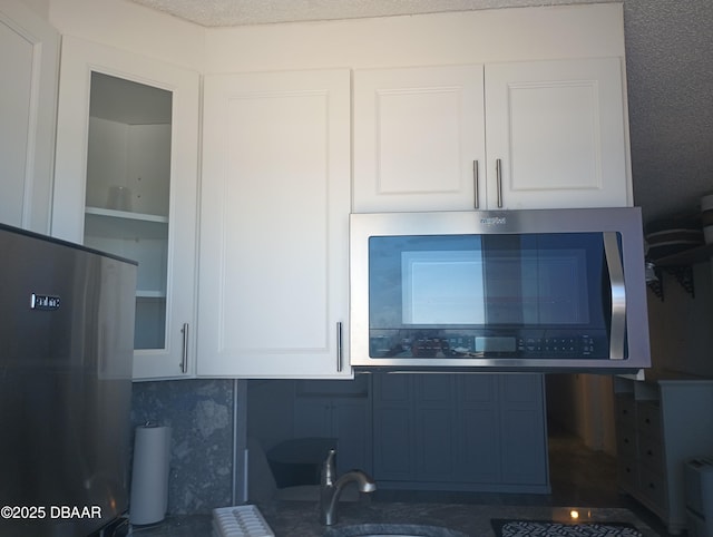 room details featuring a sink, appliances with stainless steel finishes, and white cabinets