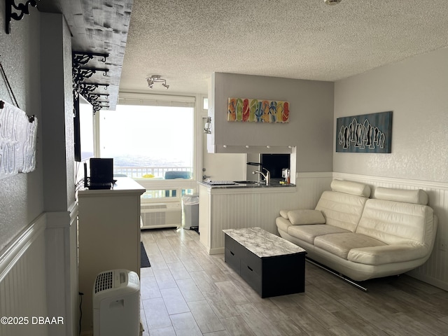 living area featuring wood finished floors, a wainscoted wall, and a textured ceiling