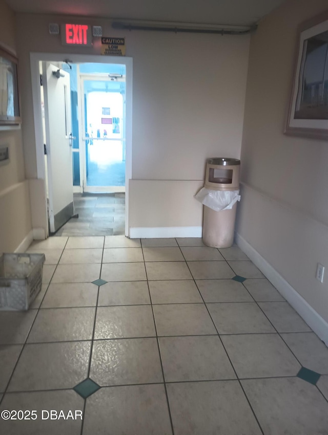 hallway featuring light tile patterned flooring and baseboards