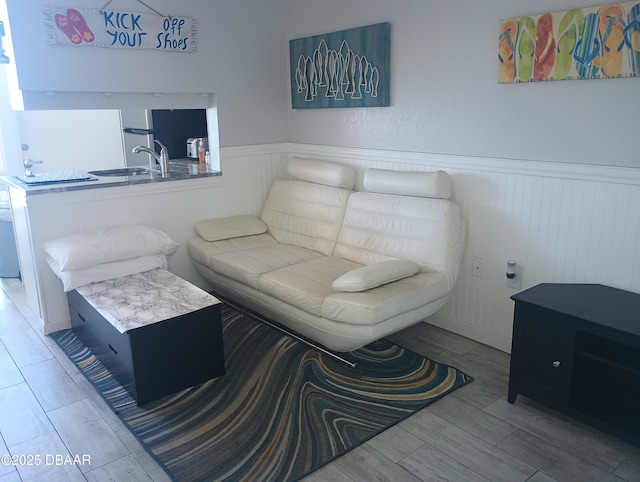 living area featuring wood finish floors and a wainscoted wall