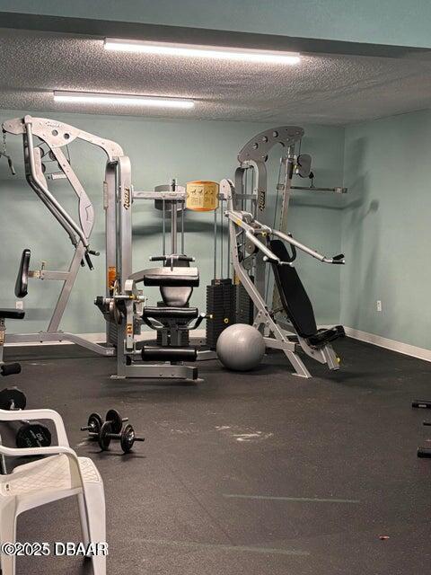 gym featuring baseboards and a textured ceiling