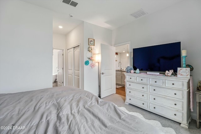 carpeted bedroom featuring sink, connected bathroom, and a closet