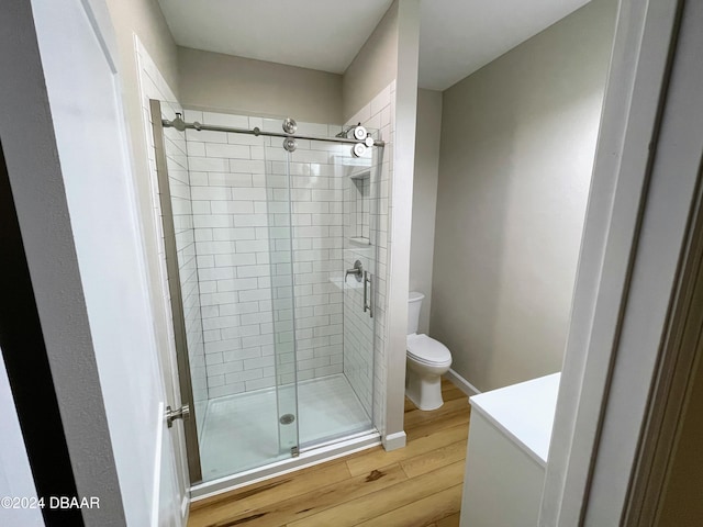 bathroom featuring hardwood / wood-style floors, an enclosed shower, and toilet