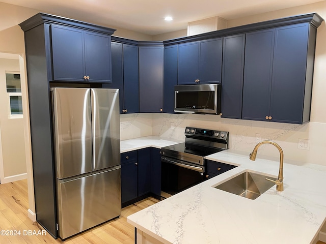 kitchen featuring blue cabinetry, light stone countertops, sink, light hardwood / wood-style flooring, and appliances with stainless steel finishes