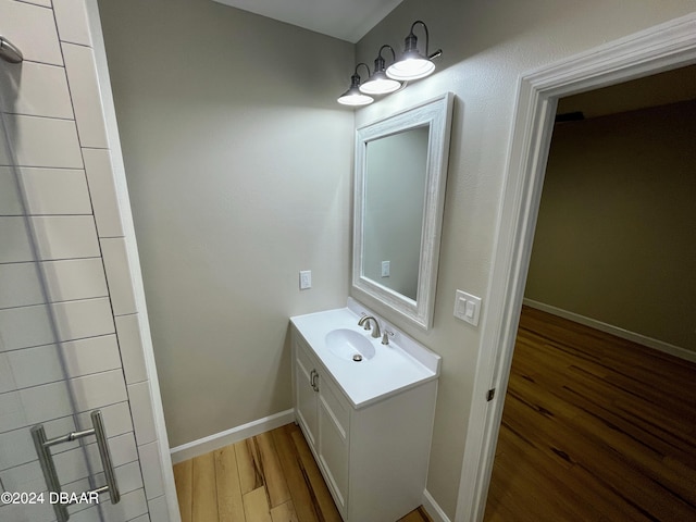 bathroom with hardwood / wood-style flooring, vanity, and walk in shower