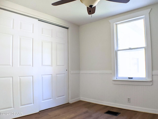 unfurnished bedroom with a closet, dark hardwood / wood-style floors, and ceiling fan