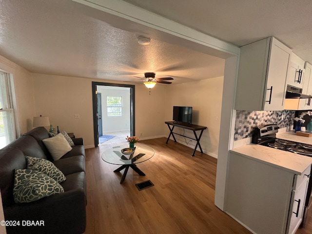 living room with ceiling fan, plenty of natural light, a textured ceiling, and hardwood / wood-style flooring