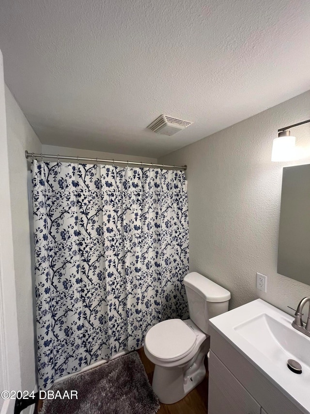 bathroom featuring hardwood / wood-style floors, vanity, a textured ceiling, and toilet