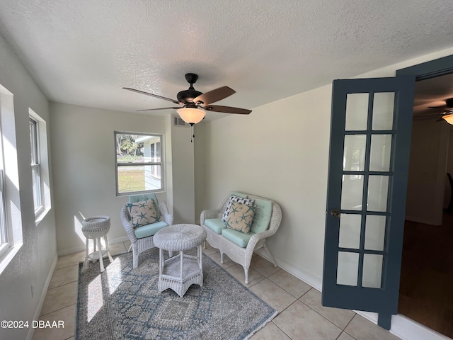 living area featuring light tile patterned floors, a textured ceiling, and ceiling fan