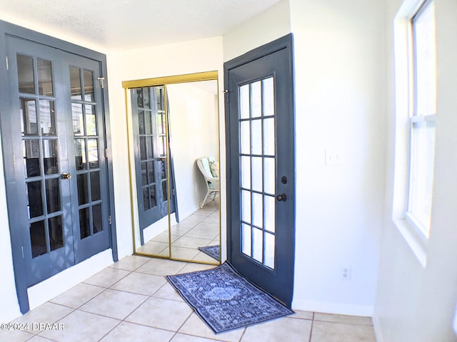 doorway to outside featuring french doors, a textured ceiling, a wealth of natural light, and light tile patterned flooring