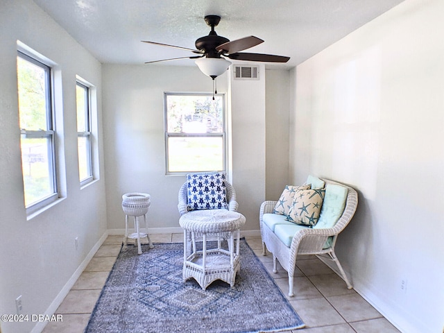 living area with ceiling fan and light tile patterned flooring