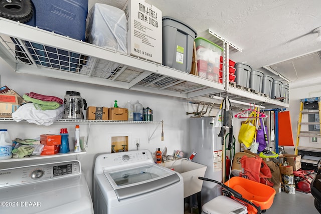 clothes washing area with a textured ceiling, washer and clothes dryer, gas water heater, and sink