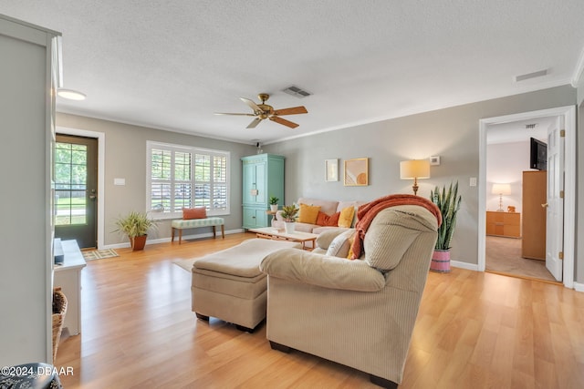 living room featuring ceiling fan, crown molding, light hardwood / wood-style floors, and a textured ceiling