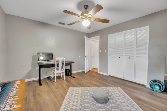 home office with light hardwood / wood-style flooring and ceiling fan