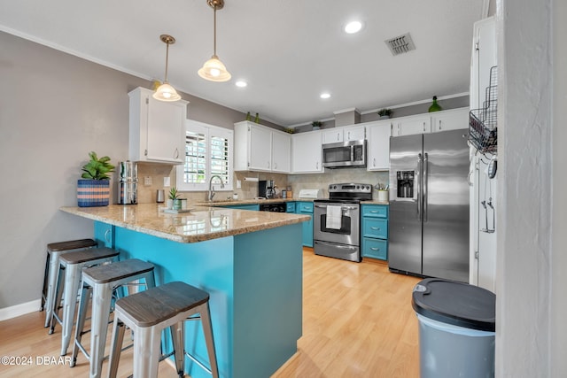 kitchen featuring white cabinetry, tasteful backsplash, decorative light fixtures, light wood-type flooring, and stainless steel appliances