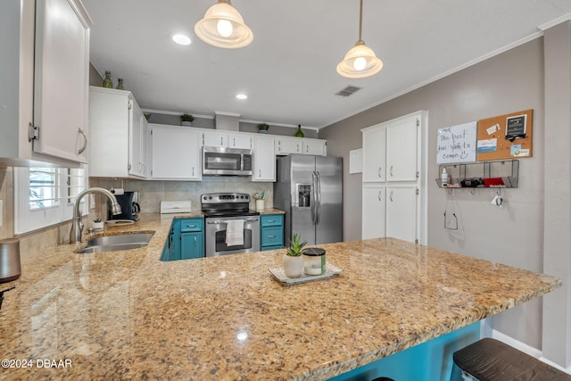 kitchen with appliances with stainless steel finishes, sink, white cabinets, hanging light fixtures, and crown molding