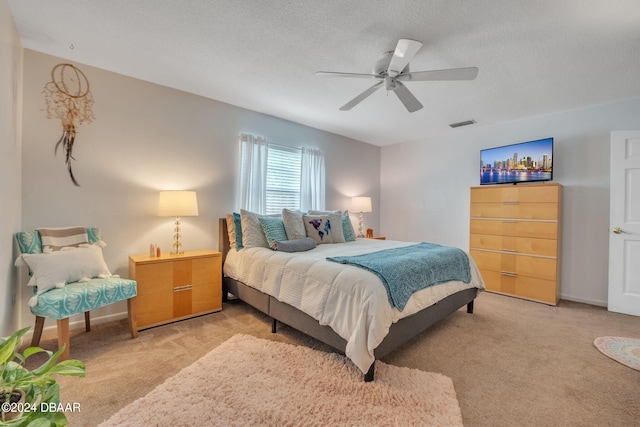 bedroom featuring ceiling fan, light carpet, and a textured ceiling