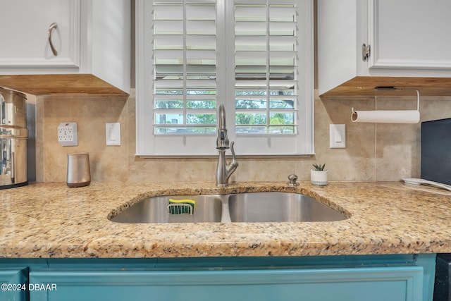 kitchen featuring white cabinetry, sink, backsplash, light stone counters, and blue cabinetry