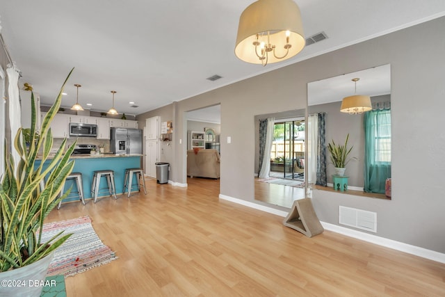 interior space with an inviting chandelier, crown molding, and light wood-type flooring