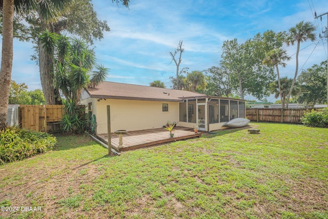 rear view of house with a yard, a deck, and a sunroom