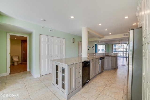 kitchen with white cabinetry, stainless steel appliances, gray cabinetry, light stone countertops, and a kitchen island