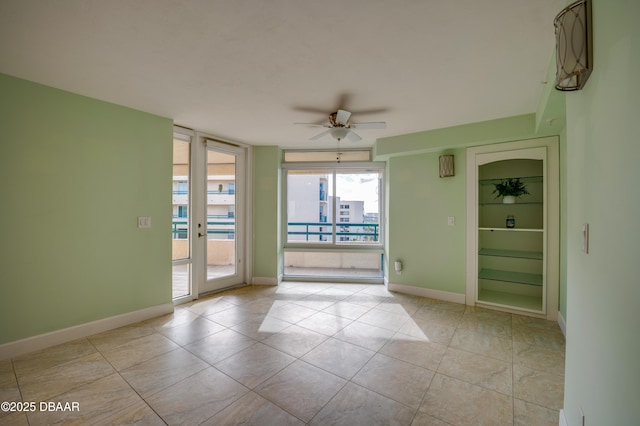 tiled spare room featuring ceiling fan and floor to ceiling windows