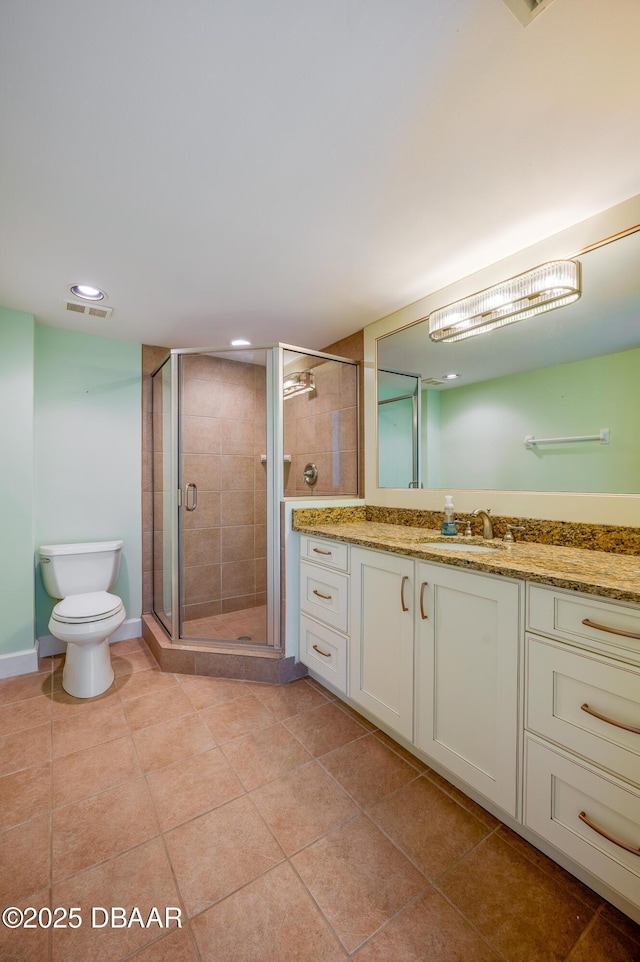 bathroom with a shower with shower door, vanity, tile patterned flooring, and toilet