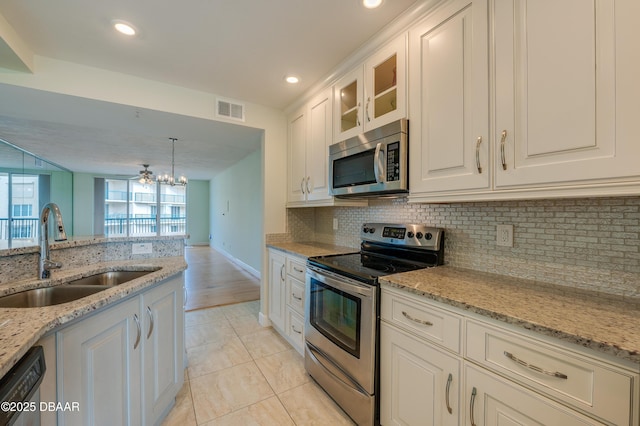 kitchen featuring appliances with stainless steel finishes, white cabinetry, sink, light stone counters, and light tile patterned floors