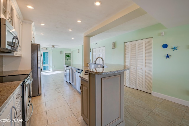 kitchen featuring white cabinetry, stainless steel appliances, an island with sink, ceiling fan, and light tile patterned floors