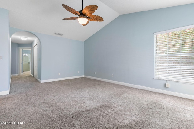 spare room featuring ceiling fan, baseboards, vaulted ceiling, carpet flooring, and arched walkways