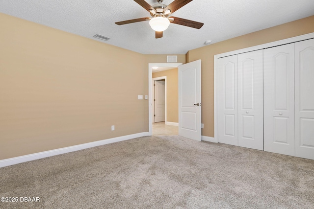 unfurnished bedroom featuring visible vents, a textured ceiling, baseboards, and carpet floors