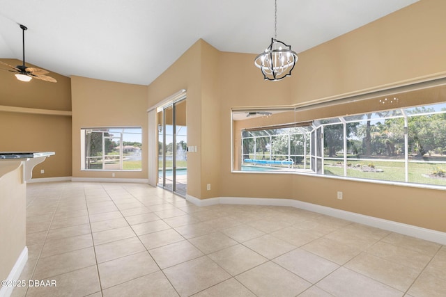 tiled empty room featuring ceiling fan with notable chandelier, high vaulted ceiling, and baseboards