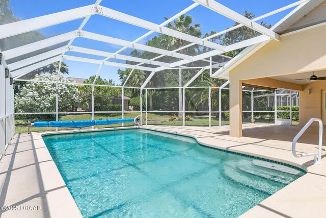 view of swimming pool with glass enclosure, a covered pool, a patio area, and a ceiling fan