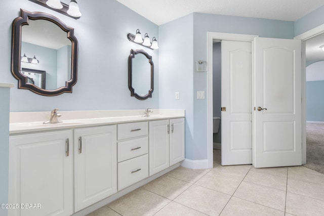 full bath featuring a sink, baseboards, double vanity, and tile patterned flooring