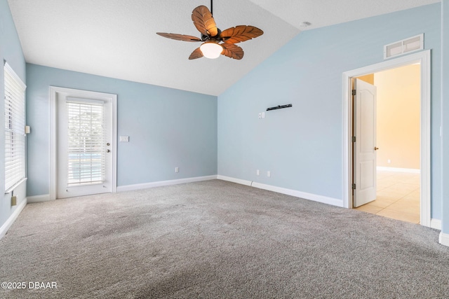 carpeted empty room featuring lofted ceiling, baseboards, visible vents, and ceiling fan