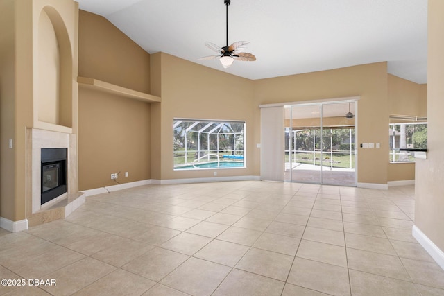 unfurnished living room with light tile patterned floors, high vaulted ceiling, a ceiling fan, and a tiled fireplace