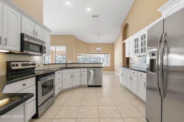 kitchen with light tile patterned floors, stainless steel appliances, backsplash, and a peninsula