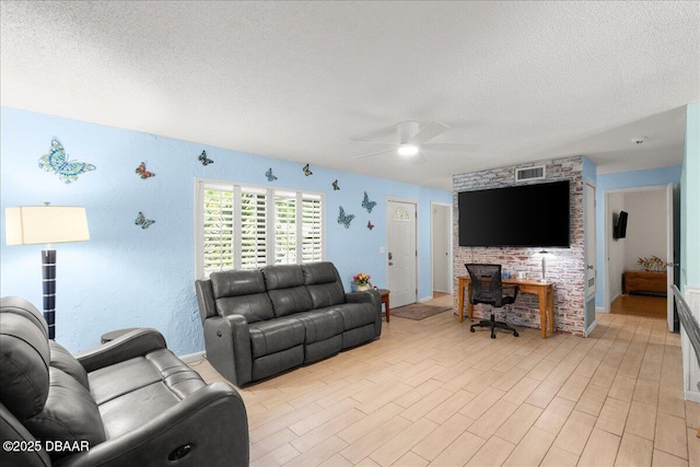 living room with ceiling fan, a textured ceiling, light wood-type flooring, and visible vents