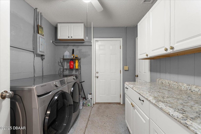 laundry area with cabinet space, washing machine and clothes dryer, a textured ceiling, concrete block wall, and ceiling fan