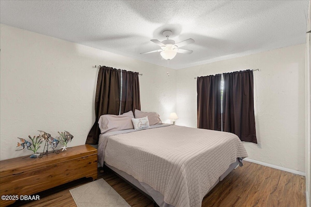 bedroom with a textured ceiling, baseboards, a ceiling fan, and wood finished floors