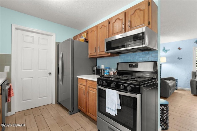 kitchen featuring stainless steel appliances, a textured ceiling, light countertops, and light wood-style flooring