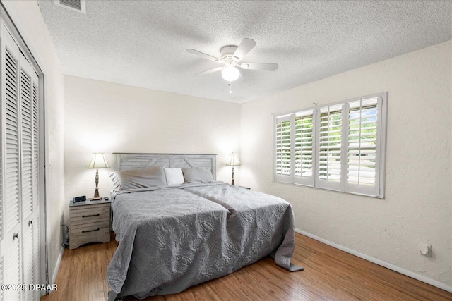 bedroom featuring a closet, wood finished floors, a textured ceiling, a ceiling fan, and baseboards