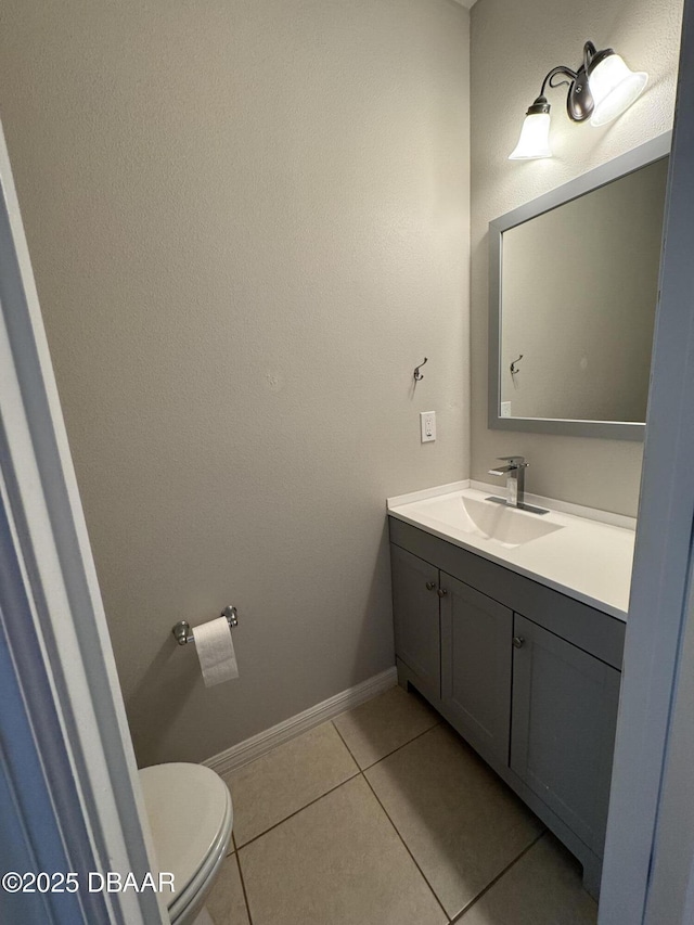 bathroom with toilet, baseboards, vanity, and tile patterned floors