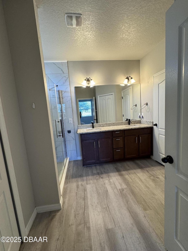 bathroom with vanity, a textured ceiling, wood-type flooring, and walk in shower