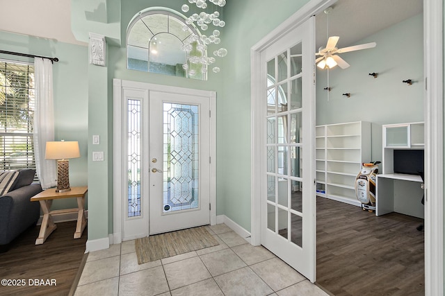 tiled entryway with ceiling fan, a high ceiling, and french doors