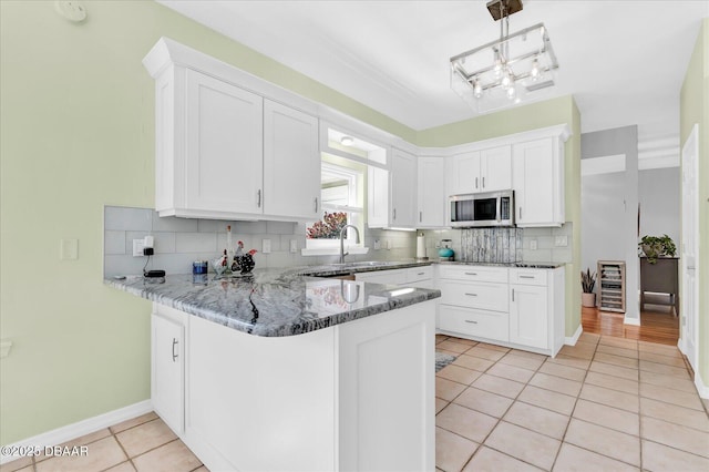 2 Bulows Lndg, Flagler Beach, FL 32136 - kitchen with stainless steel microwave, light tile patterned floors, a peninsula, backsplash, and light stone counters